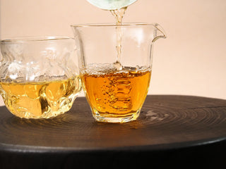 Comparison of first and second steeps of 2018 Fuding Shou Mei, lighter golden liquor beside deeper amber in two glass pitchers.