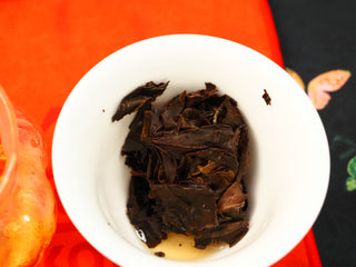 Fully steeped wet leaves from 2024 Fuding Shou Mei and Chen Pi waffle cake in a gaiwan, dark leaves with citrus peel strips visible.