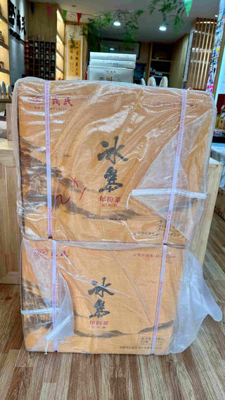 Multiple boxes of Mengku Rongshi Bingdao Aged Ripe Pu-erh coin cakes wrapped in woven plastic, stacked in a tea shop warehouse.
