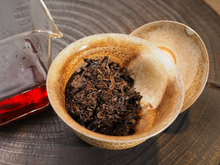 Infused wet tea leaves of Dayi 7452 ripe puerh inside a coarse clay brewing bowl after multiple steeps.