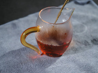 Steeped Yunnan Dark Tea liquor in a glass fairness cup showing clarity.