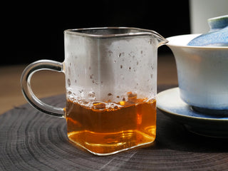 A close-up of the bright golden-orange tea soup of brewed 2020 Dayi 7542 raw puerh in a glass gongdao bei.