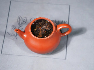 Purple clay teapot with Jingyang Golden Flower Fu Brick Tea fully infused, golden flowers gradually releasing into the hot water.