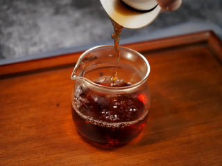 Deep red Pu-erh tea liquor from Qilin Hao Fengshan Gushu Ripe Pu-erh Tea Cake 2021 being poured into a glass Gongdao cup