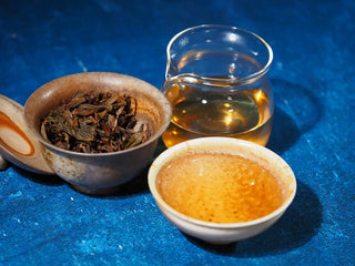 Spring Ming 2017 Aged Sheng Pu-erh Tea Cake – 400g (Lincang, Yunnan) with gaiwan, gongdao cup, and tasting cup, highlighting rich amber tea and unfurled leaves.
