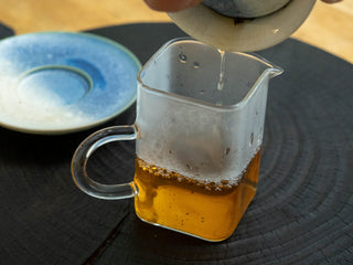 Clear golden-orange tea soup of 2006 aged raw Puerh tea poured into a glass fairness cup (Gongdaobei).