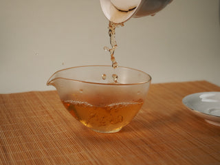 Golden amber liquor of Jing Chang Hao Mengsong Autumn Harvest 2013 raw Pu-erh poured into a glass fairness pitcher