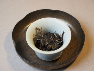 Macro shot of dry Lincang ancient tree raw puerh tea leaves highlighting premium grade material.