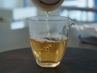 2020 Dazhai Ancient Tree Raw Pu-erh Tea – Golden Yellow Liquor Being Poured into Glass Sharing Pitcher, Showcasing Bright Clear Brew
