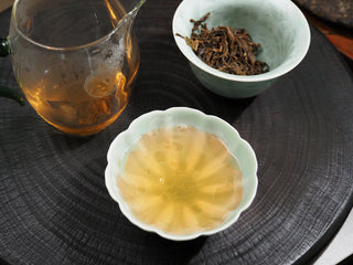 A cup of vibrant, clear golden raw puerh tea soup brewed from 2021 Dayi Guanchao Batch 2101.

