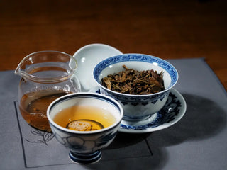Composition showing Ancient Arbor Harmony Raw Pu-erh Tea liquor, brewed leaves, and fair cup together – full presentation of color and clarity.