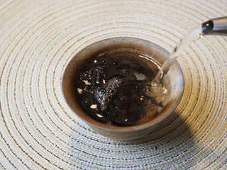 Hot water being poured over loose leaves during the brewing process of the 2005 Lincang aged raw Pu-erh tea.