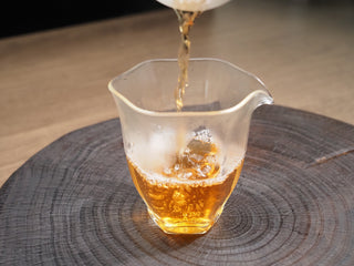 Pouring bright golden-amber tea liquor of 2021 Dayi Mi Xiang Sheng Puerh into a glass sharing cup (gongdao bei).
