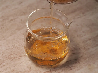 Bright golden tea liquor of Value Classic 2008 Tribute Sheng Pu-erh Tea Cake – 357g Menghai (2019 Pressed) being poured from gaiwan into fair cup