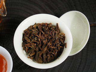 Wet, plump, and active brewed tea leaves (leaf bottom) of 2016 Dayi 7532 Sheng Puerh in a white Gaiwan, showing leaf vitality.
