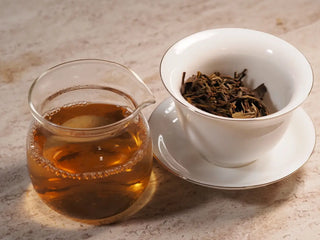 Gaiwan with brewed wet leaves and a clear gongdao cup filled with bright amber liquor from 2019 Qilin Tribute Sheng Pu-erh Tea Cake – Ancient Arbor 357g.