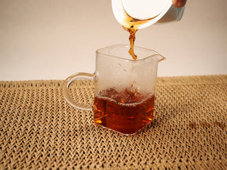 First steep of 2020 Bojun Ripe Pu-erh poured into a glass pitcher, the liquor a clear deep reddish amber.