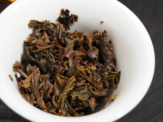 Steeped wet tea leaves (cha di) of 2021 Dayi Mi Xiang Raw Puerh in a gaiwan, showing healthy, thick green-brown leaves.
