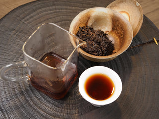 A complete Chinese Gongfu tea session setup for 2017 Dayi 7452 ripe puerh, including a glass pitcher, cup, and brewing bowl.