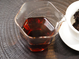 Clear, bright burgundy-red tea soup of 2021 Dayi 7572 ripe puerh in a glass gongfu pitcher.