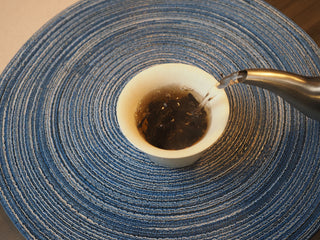 Pouring hot water to rinse and brew the 2005 Lincang vintage Shou Pu-erh tea in a gaiwan