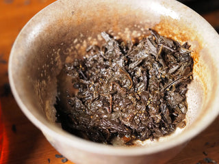 Wet, expanded tea leaves of YXT Jingyang Fu Tea Ximanzi 2018 after brewing, filling a clay brewing vessel.