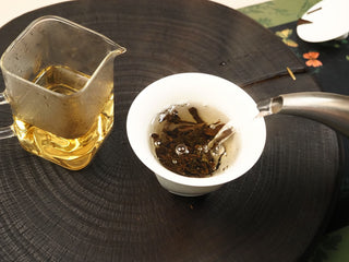 Boiling water poured into a white gaiwan over 2014 sun-dried White Peony waffle cake, second infusion beginning.