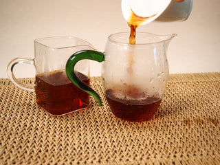 2020 Bojun Ripe Pu-erh poured into two glass pitchers (one green handle, one plain), liquor a clear deep reddish amber.