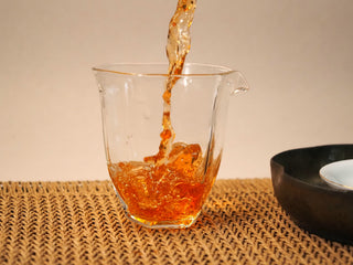 First steep of Bojun Ripe Pu-erh 7.0 poured into a glass pitcher, the liquor a clear deep reddish amber.