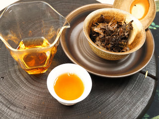 Complete gongfu setup for Gold Brick 2012 aged White Peony: glass fairness pitcher, tasting cups, gaiwan and brick on wooden tray.