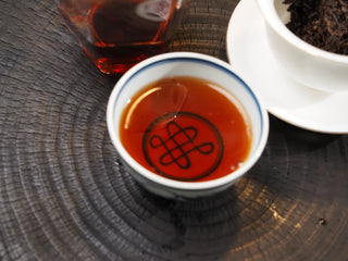 A cup of brewed Dayi 7572 ripe puerh tea showing its rich, thick, and bright reddish-brown liquor.