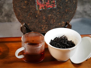 Qilin Hao Fengshan Gushu Ripe Pu-erh Tea Cake 2021 displayed with Gaiwan and tea cup, showing rich red liquor and elegant presentation