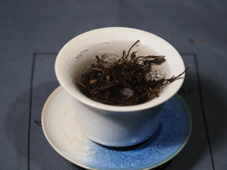 Delicate early spring Bulang Puerh tea leaves steeping inside a white porcelain Gaiwan.