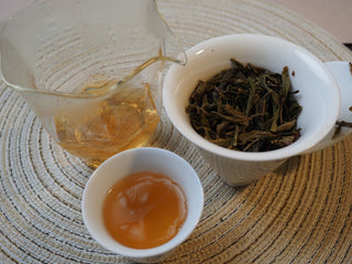 Complete tea service setting featuring brewed 2026 Tan Chun raw Puerh tea soup, fairness pitcher, and wet leaves.