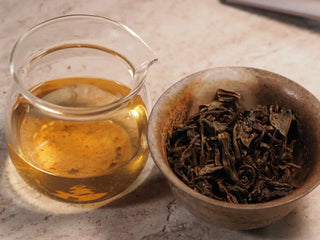 Gaiwan with steeped leaves beside fair cup filled with bright tea liquor from Value Classic 2008 Tribute Sheng Pu-erh Tea Cake – 357g Menghai