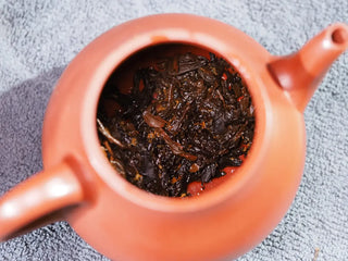 Wet tea leaves (bottom) of On Taoism Fu Brick Tea after multiple infusions.