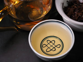 Close-up of tea liquor from Yunnan Jinggu White Peony Tea Cake 357g in tasting cup, displaying golden-yellow color and clarity