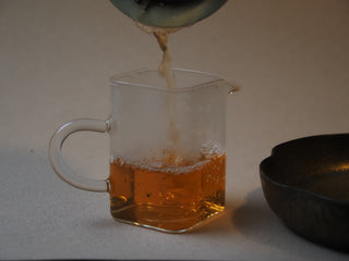 Bright golden-yellow raw puerh tea liquor being poured into a fair cup (Gongdaobei).