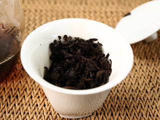 Wet leaf of 2020 Bojun Ripe Pu-erh after multiple steepings, dark brown fermented leaves fully opened in a white porcelain gaiwan.