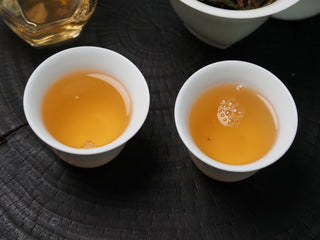 2020 Dazhai Ancient Tree Raw Pu-erh Tea – Two White Porcelain Cups Filled with Bright Golden Liquor, Perfect for Sharing
