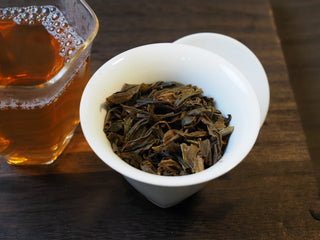 Infused wet ancient tree sheng Pu-erh tea leaves in a gaiwan