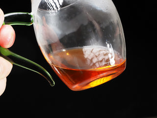 Pouring out the first light amber tea wash rinse from Gaiwan into glass Gongdao Bei pitcher