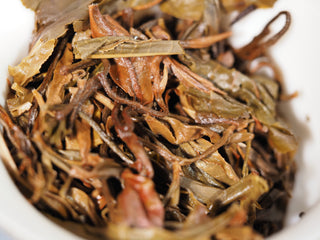 Macro view of high-quality spent ancient tree Puerh leaves from Lao Man'e, proving pure and carefully processed material.