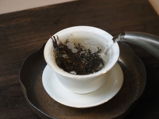 Hot water steeping loose raw pu-erh tea leaves during traditional Chinese tea ceremony
