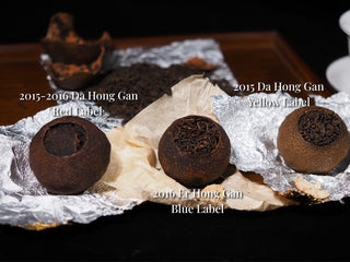Three unwrapped whole dried citrus Pu-erh tea balls showing different peel maturity levels on tinfoil.