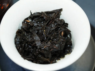Spent leaves of the Master-Crafted Golden Flower Fucha in a white bowl after multiple infusions.