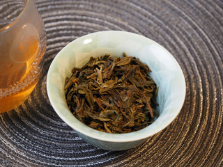 Bright and clear brewed tea liquor of 2025 Tan Chun raw Puerh served in a white tasting cup.