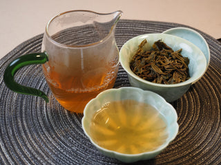 Complete tea service setting featuring brewed 2025 Tan Chun raw Puerh tea soup, fairness pitcher, and wet leaves.