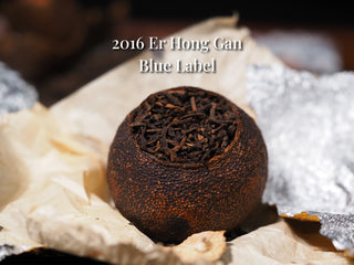Single unwrapped Tengma Er Hong Gan citrus Pu-erh tea ball showing a slightly lighter semi-ripe peel.