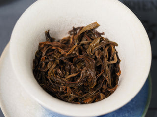 Macro shot of wet, spent tea leaves in a Gaiwan showing the fresh, tender leaf-bottom of 2023 Bulang Buds.